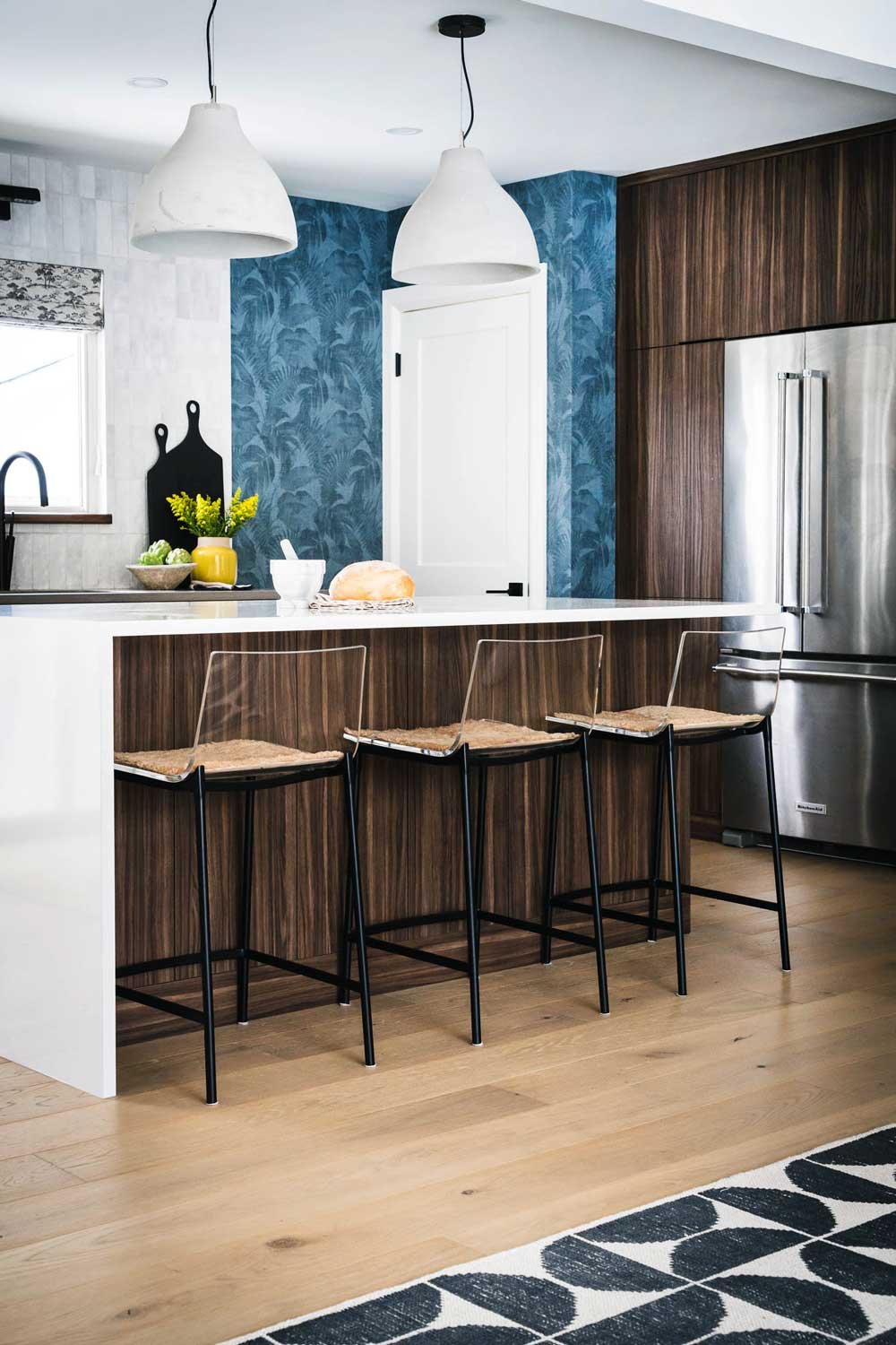 A kitchen with blue wallpaper and wood paneling.