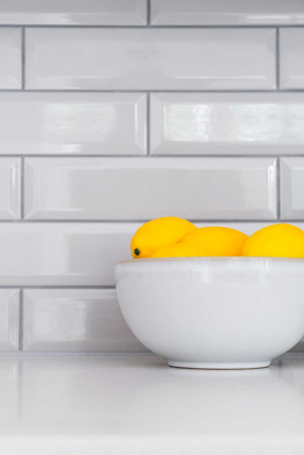 Lemons in a bowl in a white kitchen.
