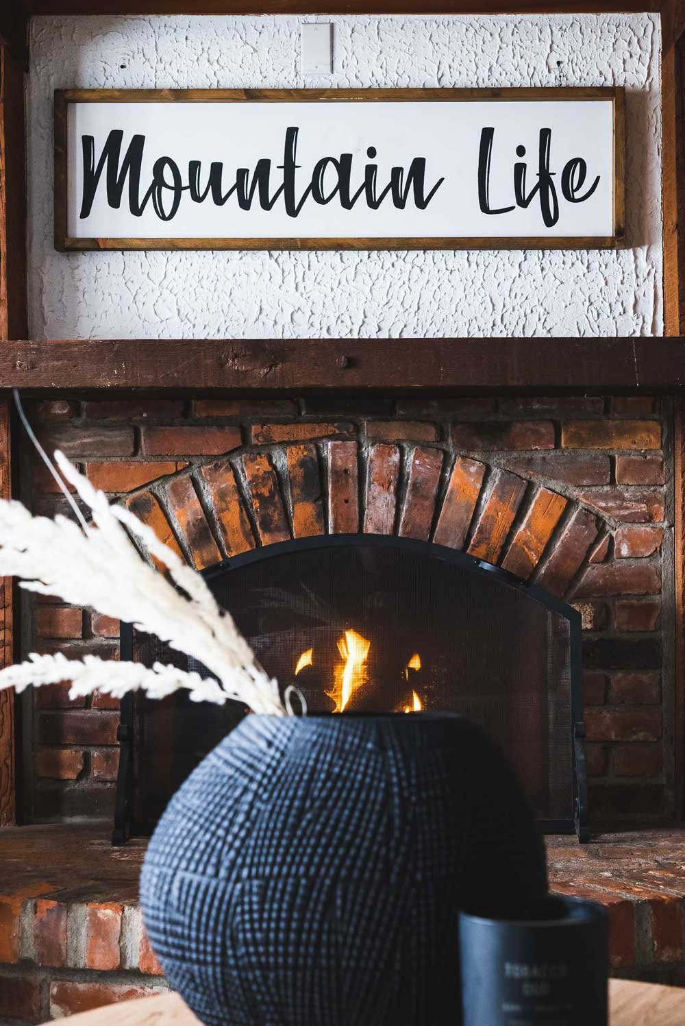 A sign above a fireplace that says mountain life.
