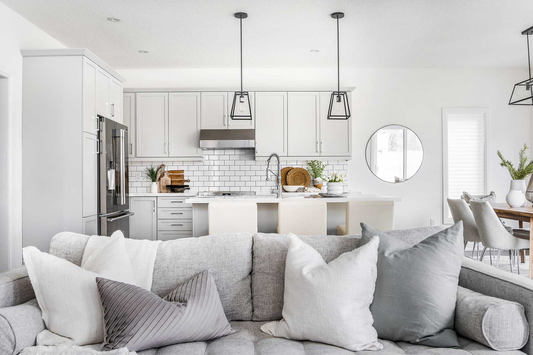 A white kitchen with white subway tiles and grey cabinets.