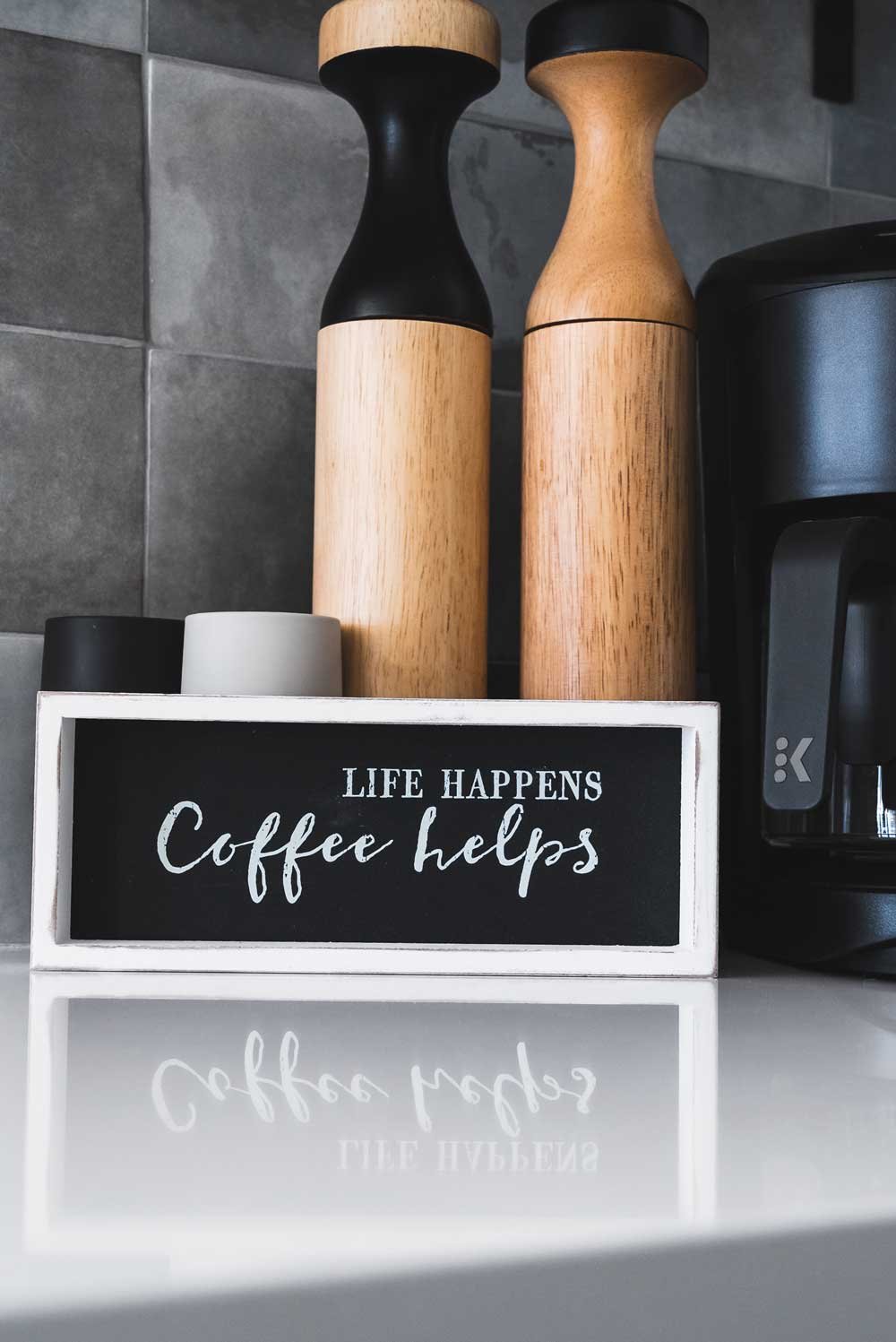 A sign in a black and white kitchen that says coffee helps. This is taken during a real estate photo shoot at an Airbnb rental in the Blue Mountains.